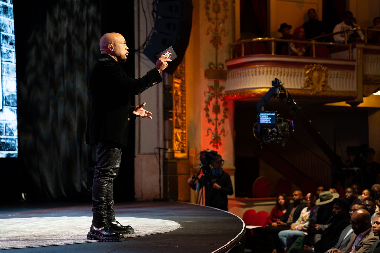 A presenter speaks on a theater stage