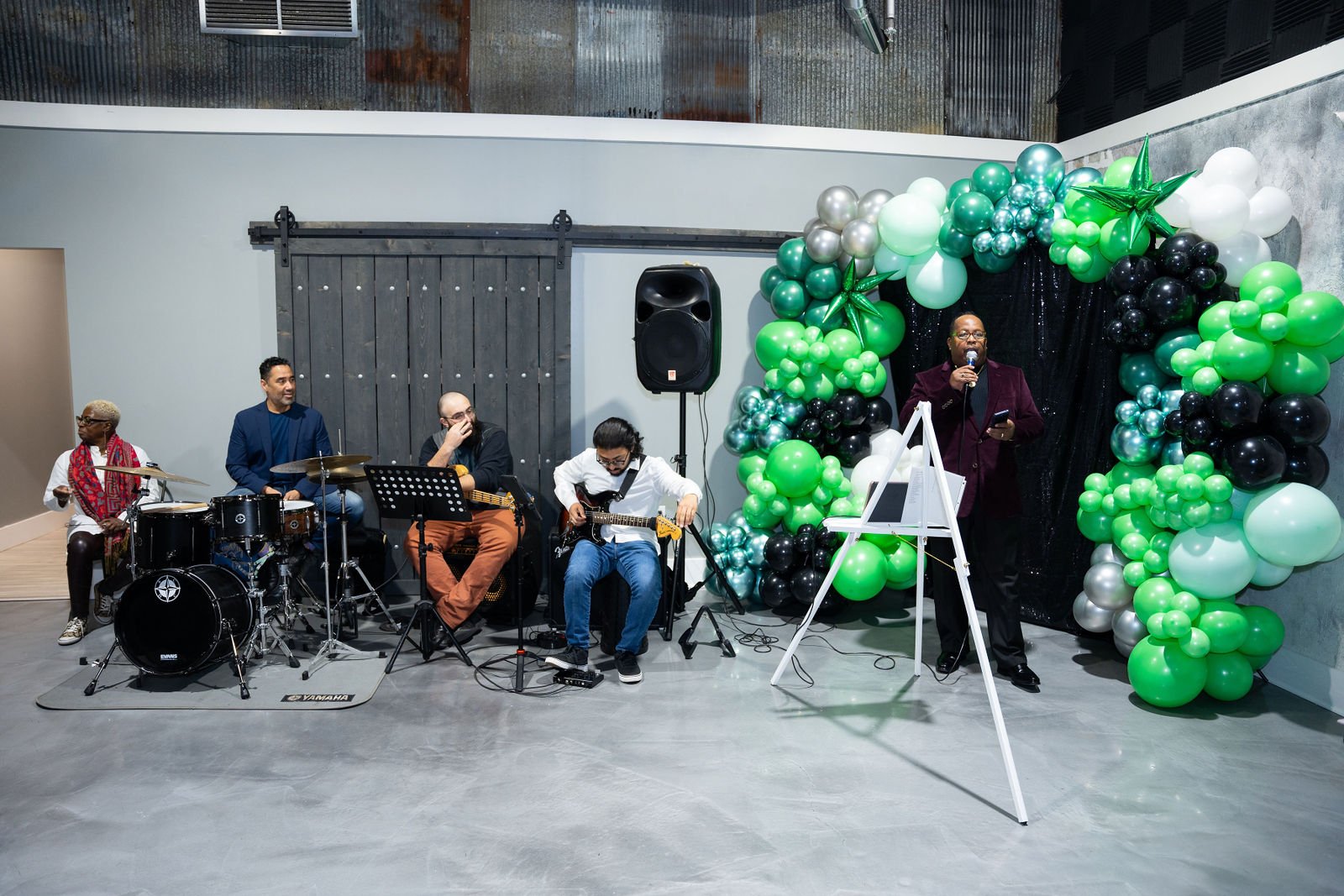 Guests gather outside beneath green and black balloons