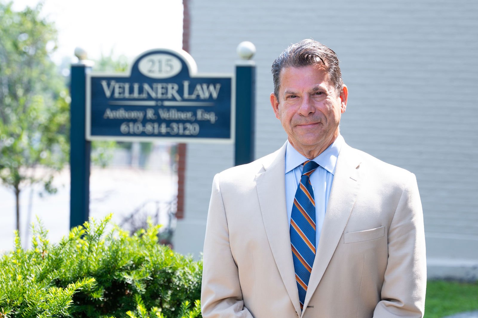A man in a suit poses outside a law office
