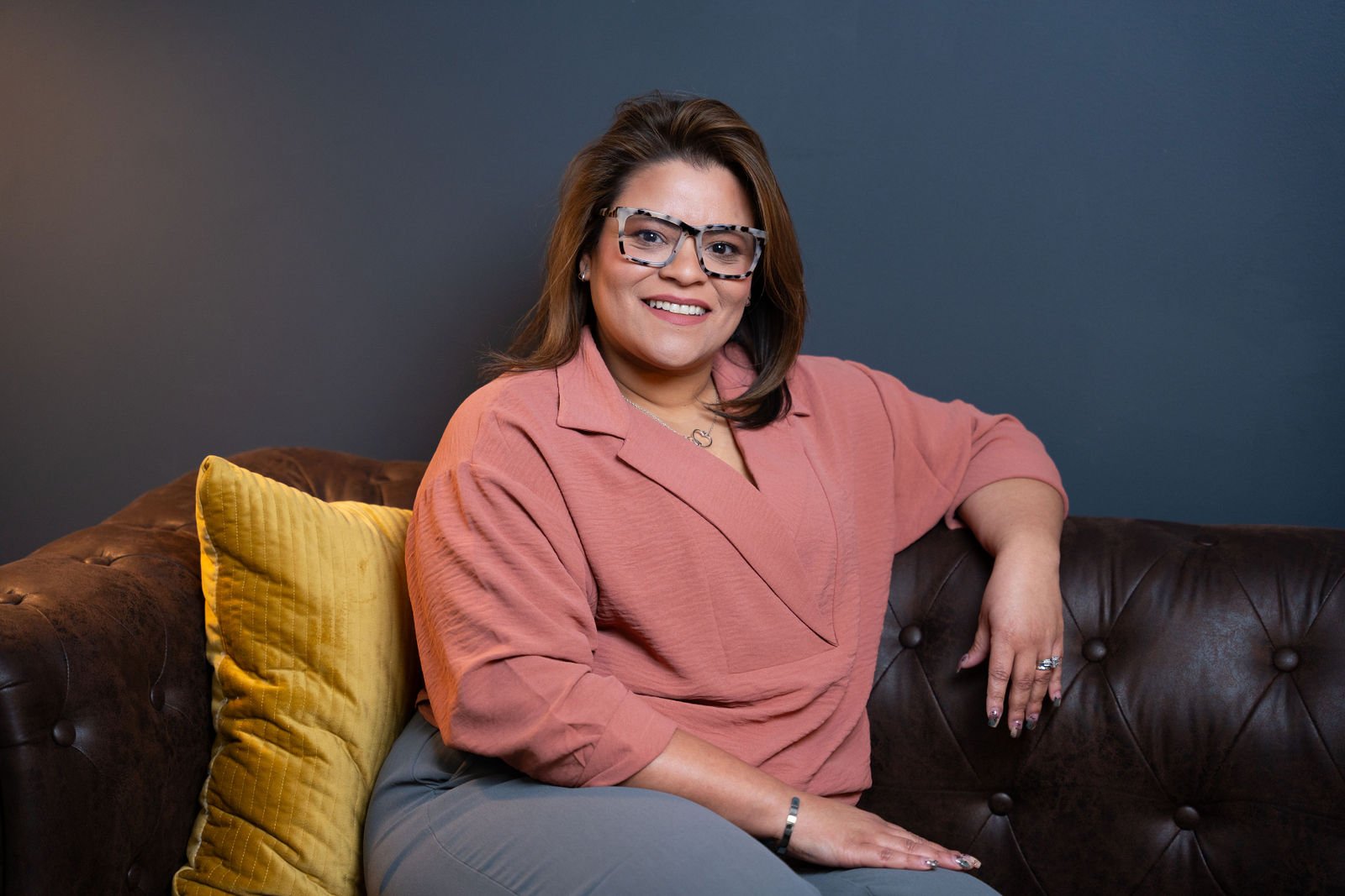 A woman in a pink blazer poses for a professional portrait