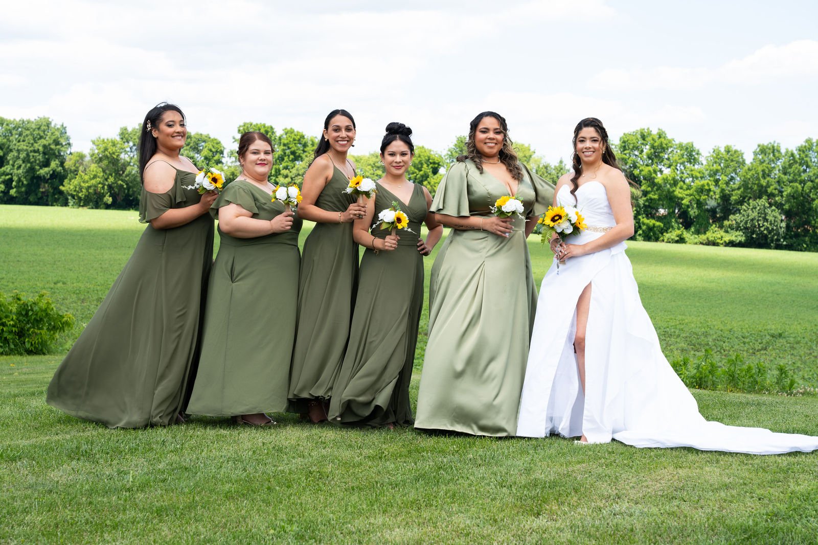 A bride poses with her wedding party on a lawn
