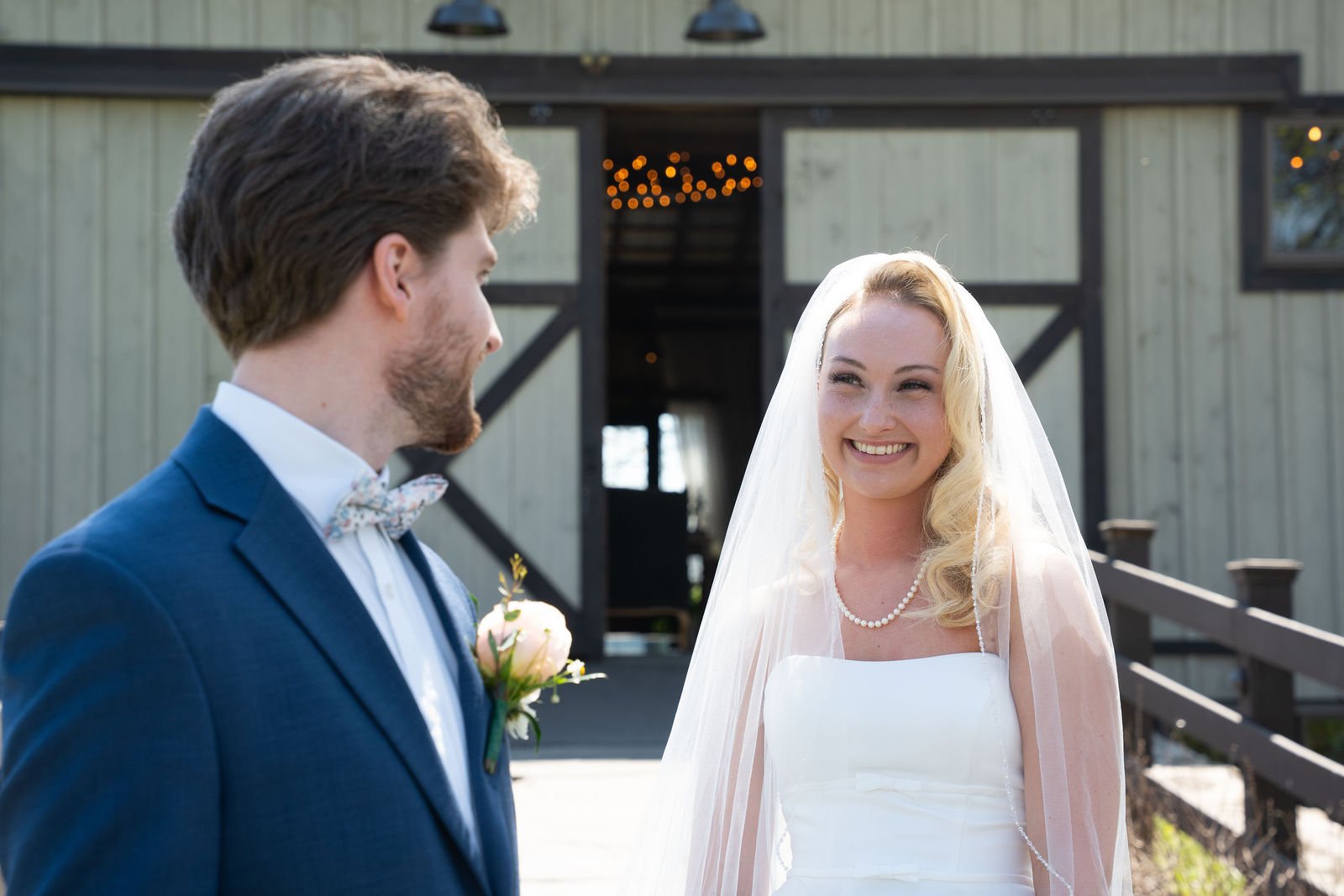A bride and groom face each other outside their venue