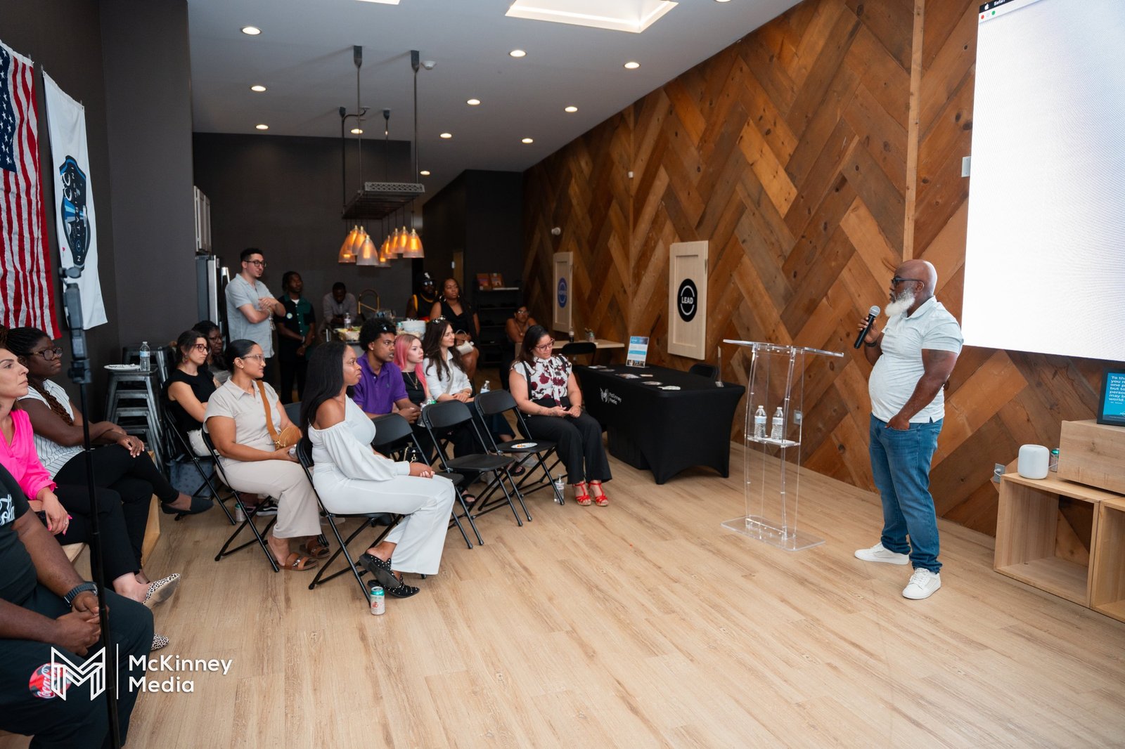 A speaker at the lectern addressing the room at Headshot Happy Hour