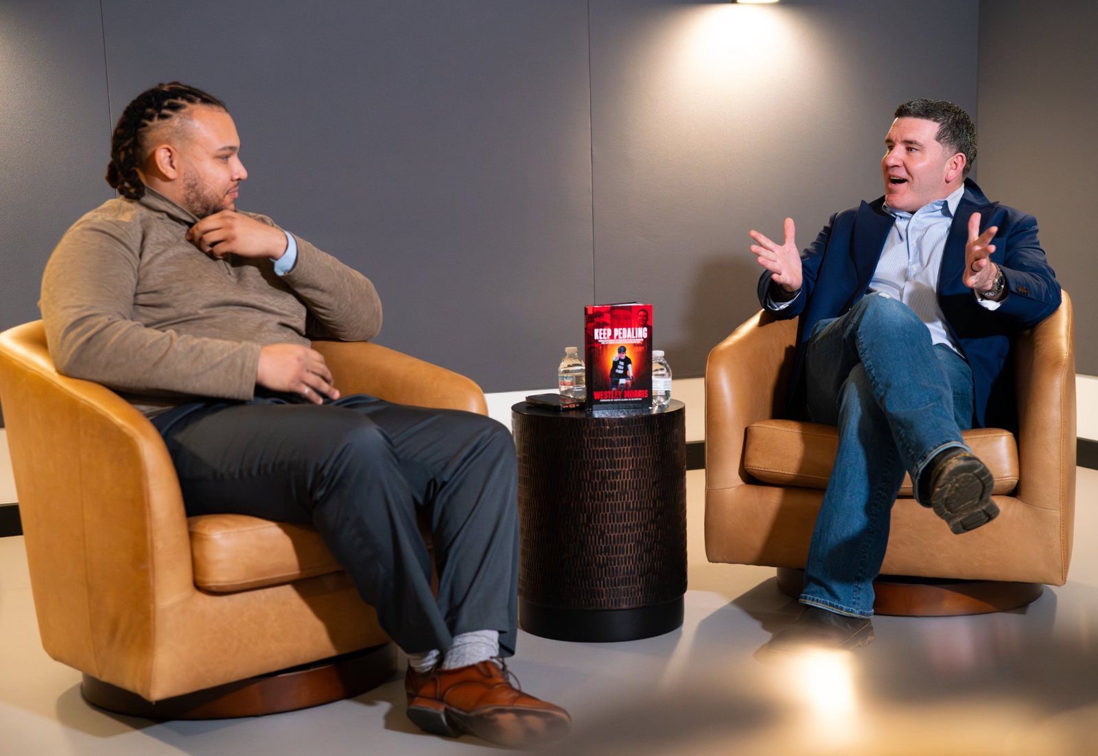 Two-camera studio interview set with warm side lighting and two armchairs